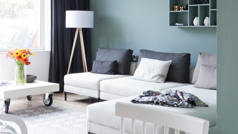canapé moderne blanc et table sur roues dans salon au mur vert poudré