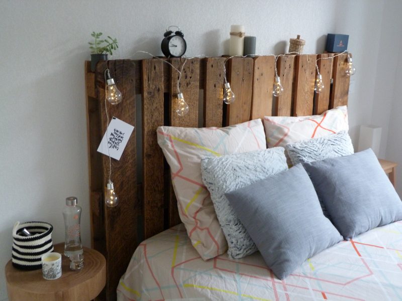 ampoules lumineuses accrochées à une tête de lit en palette recyclée