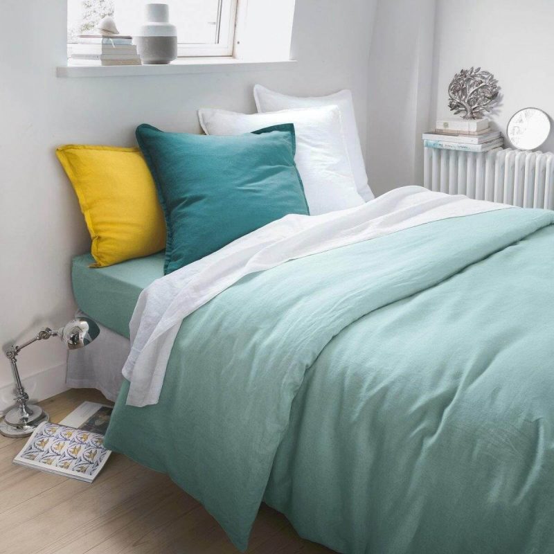 linge de lit et coussins verts et blancs sur un lit minimaliste