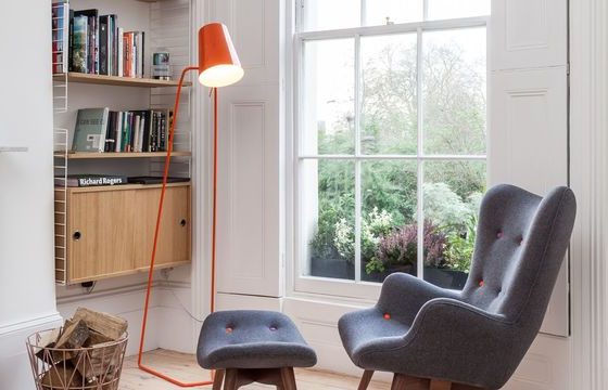 coin lecture cocooning avec fauteuil et repose pieds sous un lampadaire