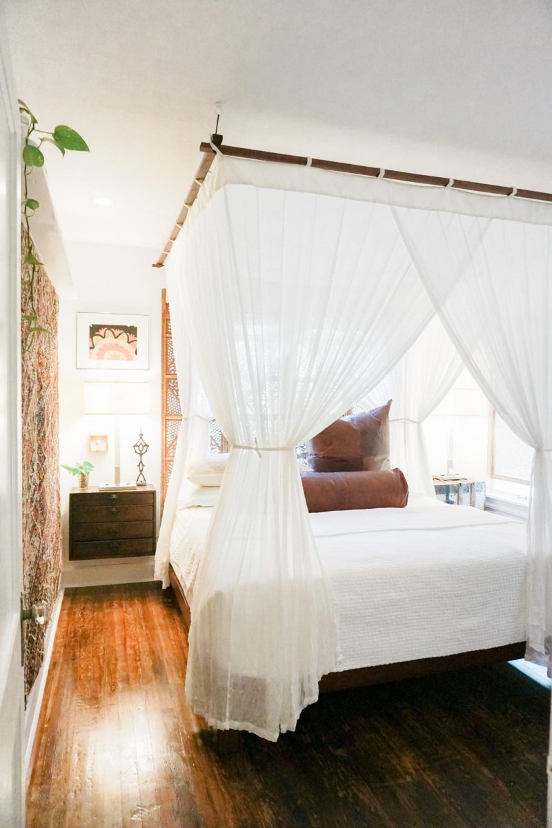 chambre de style colonial avec lit baldaquin et rideaux fins blancs