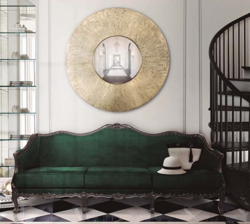 canapé vert indigo en velours sous grand miroir rond doré