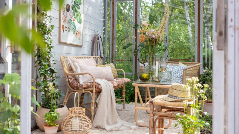 mobilier en osier et plantes fleuries dans une véranda à déco jardin d'hiver