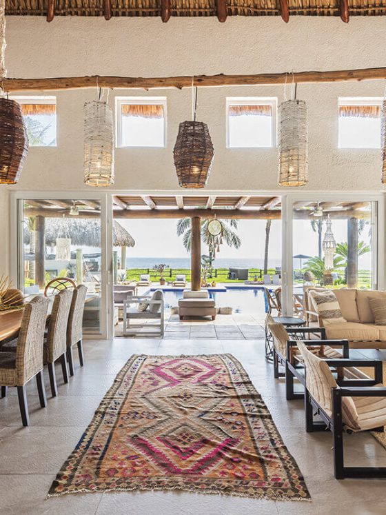 suspensions en osier accrochées à un tronc d'arbre suspendu au dessus d'une table à manger et d'un salon déco ethnique
