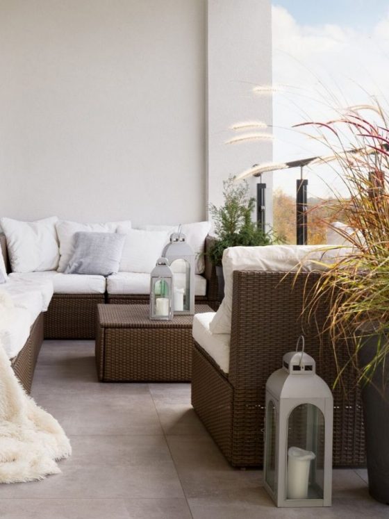 canapé d'angle habillé de coussins blancs pour aménager un balcon en longueur