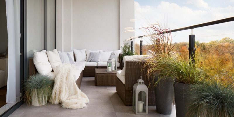 canapé d'angle habillé de coussins blancs pour aménager un balcon en longueur