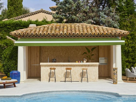 aménagement pool house d'aspect symétrique, avec un espace bar et trois hauts tabourets