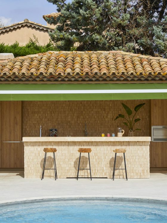 aménagement pool house d'aspect symétrique, avec un espace bar et trois hauts tabourets