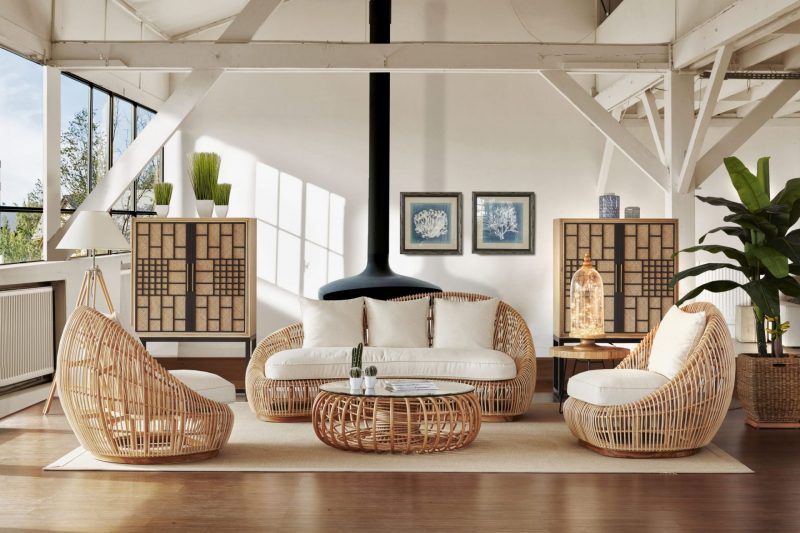 Un salon contemporain, grand et lumineux, avec un poêle suspendu, un canapé et des fauteuils en rotin