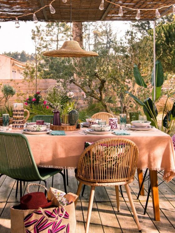 Une table d'été sur la terrasse, joliment décorée avec des couleurs pastel et des matériaux naturels