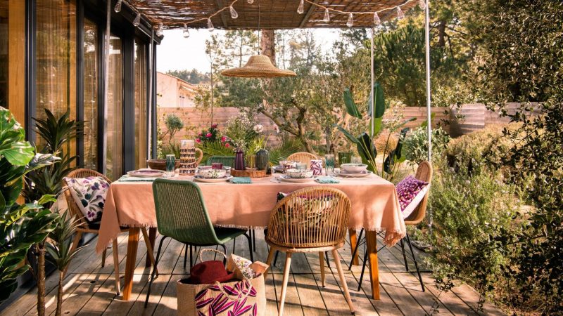 Une table d'été sur la terrasse, joliment décorée avec des couleurs pastel et des matériaux naturels