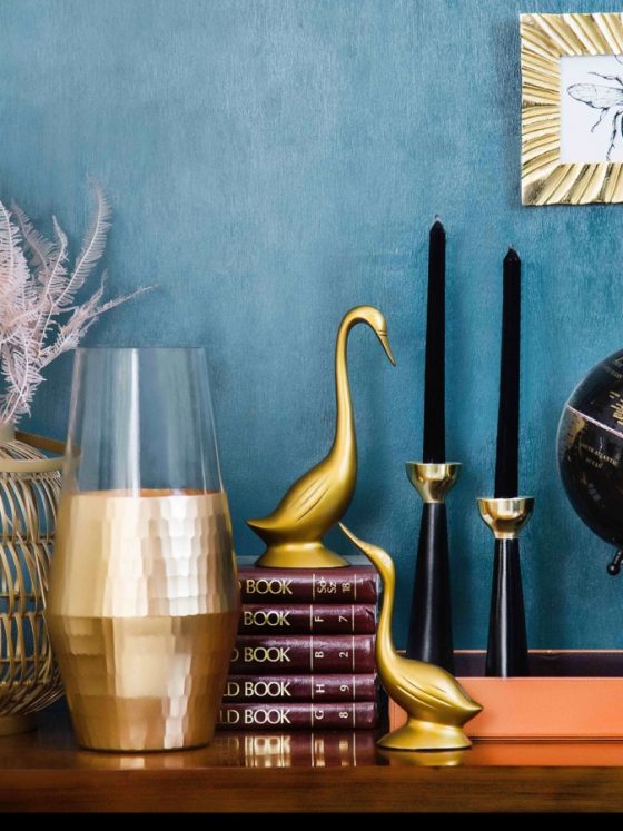 Un assortiment d'objets déco tendance sur la commode : des bougies, une mappemonde, des livres, une statuette, etc.