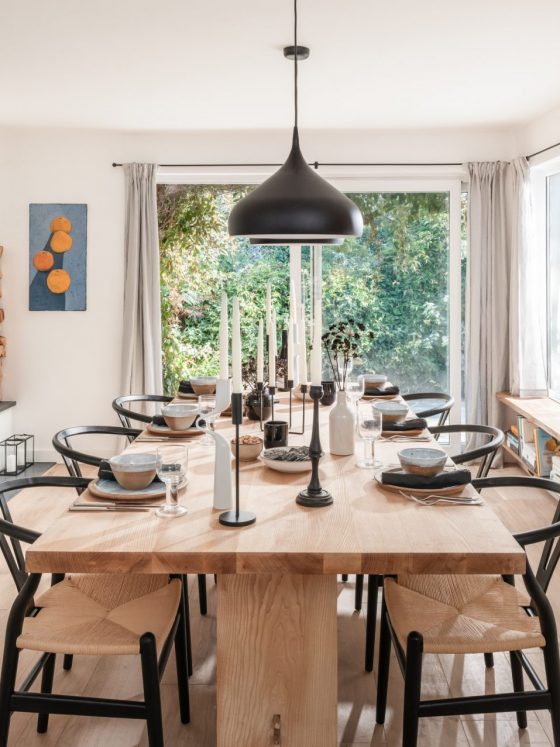 La salle à manger scandinave est aménagée avec des chaises nordiques et une grande table en bois